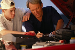 Dad showing son how to follow instructions exactly to repair his car