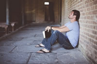 man sitting with his back to a brick wall praying, are some people not worth saving?