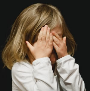 little girl covering her eyes in shame and guilt