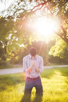 man praying on knees in sunshine